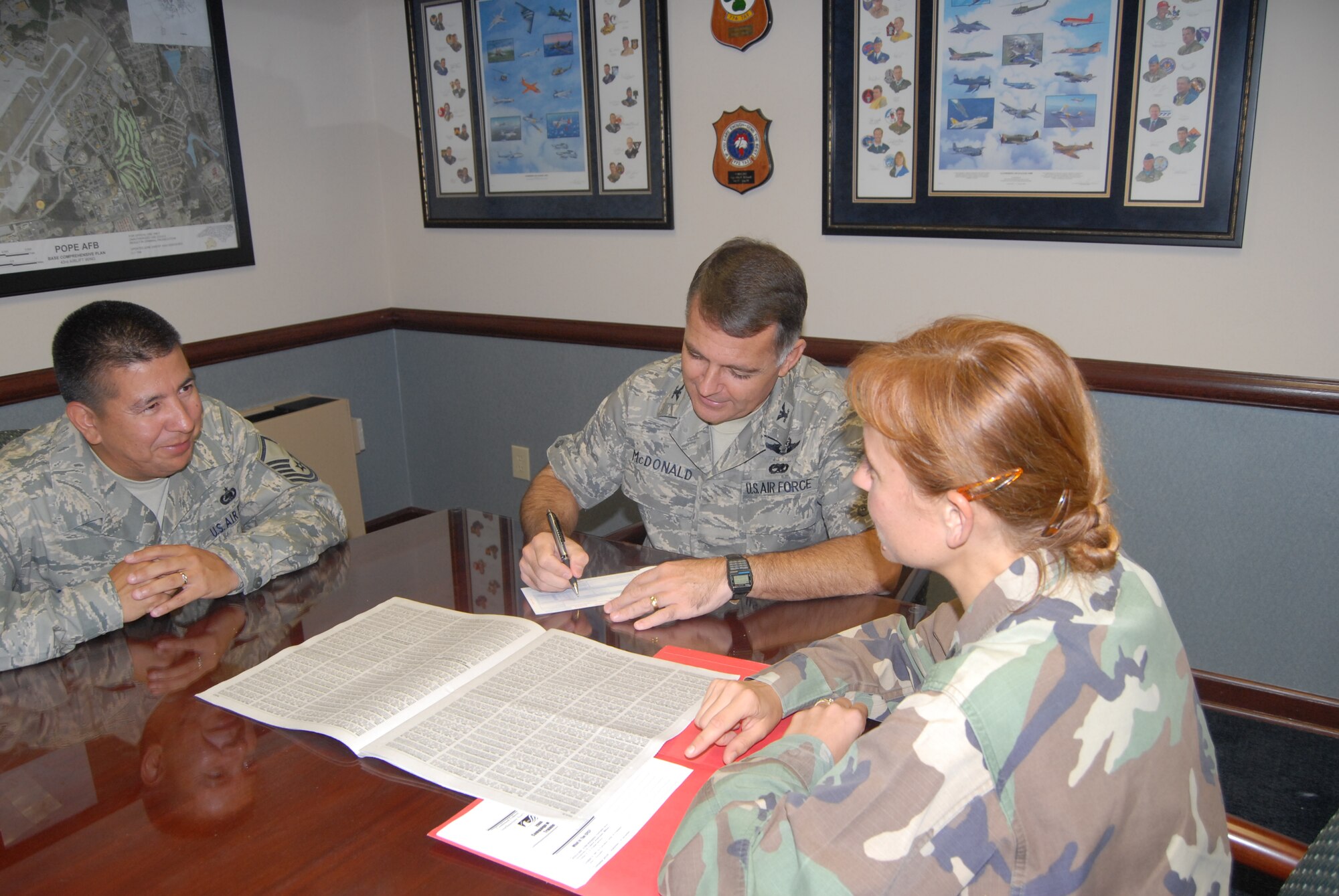 Col. John McDonald, 43rd Airlift Wing Commander, signs his Combined Federal Campaign pledge card in front of Capt. Dana Longo and Master Sgt. Patrick Garcia, both CFC campaign managers. Pope’s goal is $110,000 and as of Monday had reached nearly 75 percent of that. (U.S. Air Force Photo by Airman 1st Class Mindy Bloem)