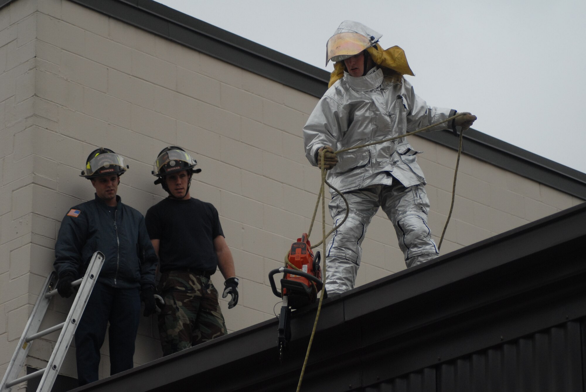 Airman 1st Class David Schuyler, 43rd Civil Engineer Squadron firefighter, lowers equipment to the ground from the roof, while Joseph Bruno (left) and Senior Airman Kyle Brown (right), also 43rd CES firefighters, provide support. (U.S. Air Force Photo by Airman 1st Class Mindy Bloem)