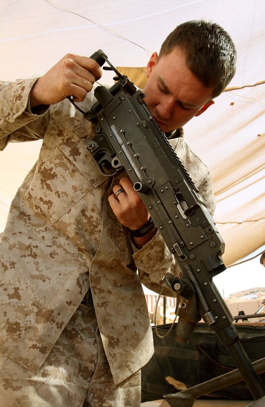 Cpl. Dennis D. Merritt, a small-arms technician with Headquarters and Service Company, 1st Light Armored Reconnaissance Battalion, Regimental Combat Team 5, prepares a M240E1 machinegun to be fired by Marines of his company at Camp Korean Village, Iraq, Oct. 4. "We need to make sure the weapons we issue are ready to go. If something malfunctions during firing, we also need to be there to fix it and get the gun back on the line," said Merritt, 21, from South Lake Tahoe, Calif.::r::::n::