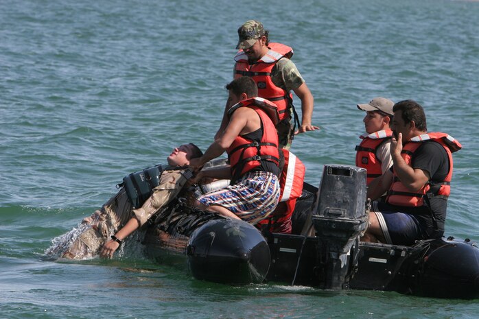 Petty Officer 3rd Class Cody S. Miller, a sailor instructor with Riverine Squadron 3, Riverine Detachment 2, 3rd Battalion, 7th Marine Regiment, Regimental Combat Team 5, is pulled back into the boat by Iraqi policemen after simulating an unconscious man-overboard at Lake Qadisiyyah, Iraq, Oct. 4. The policemen ran scenarios to practice the patrolling maneuvers they had learned from the Riverines. The policemen are taking a 21-day course to learn basic seamanship that will help them patrol the Euphrates River.  ::r::::n::