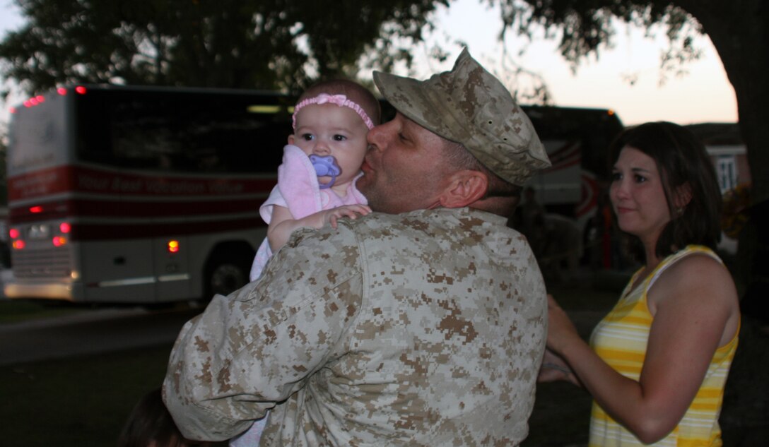 Gunnery Sgt. Prino Bonzani, ammunition chief, 24th Marine Expeditionary Unit, kisses his baby girl as his wife watches through teary eyes at the 24th MEU's homecoming.