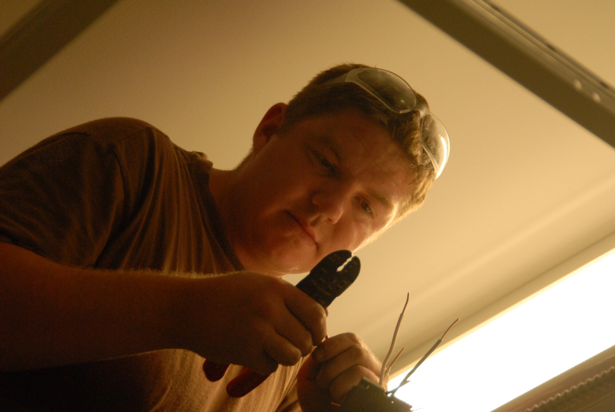 Senior Airman Mark Thompson, a power production specialist, strips wires during electrical upgrades to the Mintos Armory. (Photo by Senior Airman Jason Ketterer, Kentucky Air National Guard.)