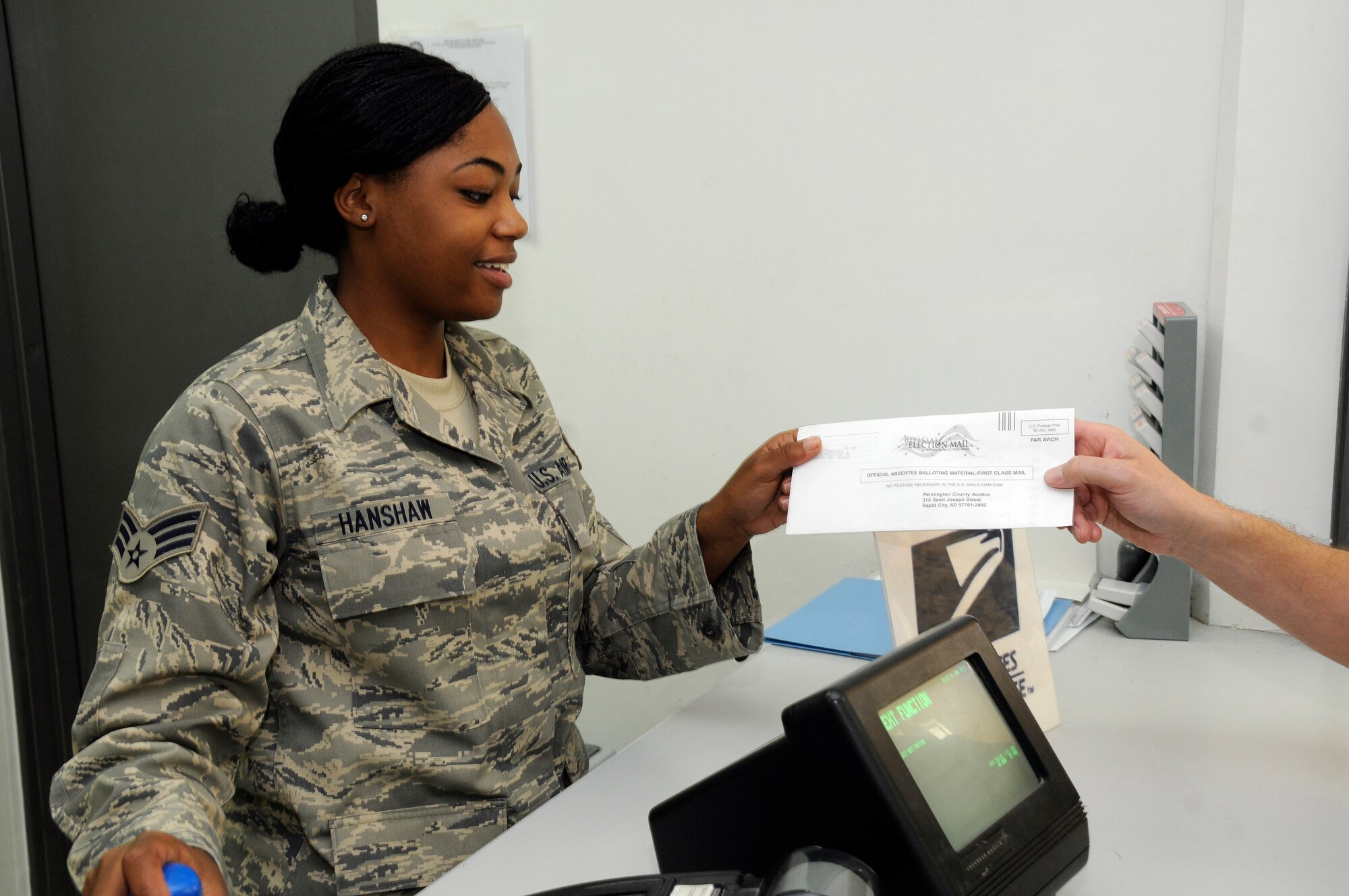 Senior Airman Ashley Hanshaw, a postal clerk with the 379th Expeditionary Communications Squadron, receives a completed absentee ballot to be mailed October 3, 2008, at an undisclosed air base in Southwest Asia.  Absentee ballots are given top priority for mail processing during election season in order to provide the best chance to have votes count.  Airman Hanshaw, a native of the Bronx, N.Y., is deployed from Dobbins Air Force Base, Ga., in support of Operations Iraqi and Enduring Freedom and Joint Task Force-Horn of Africa.  (U.S. Air Force photo by Tech. Sgt. Michael Boquette/Released)