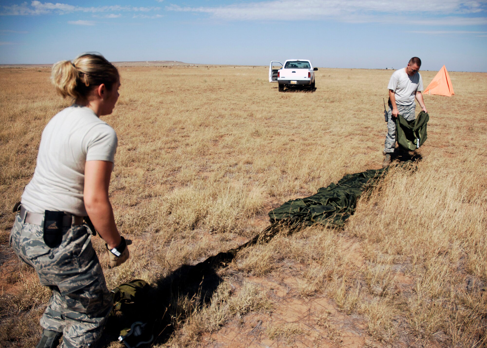 Senior Airman Helen Eberly and Staff Sgt. Jerimy Pickering recover a parachute at the Melrose Air Force Range, N.M., during an exercise Sept. 23. Airmen pack, inspect, and recover the loads that are used for airdrop training. Airman Eberly and Sergeant Pickering are assigned to the  27th Special Operations Logistics Readiness Squadron. (U.S. Air Force photo/Airman 1st Class Evelyn Chavez) 