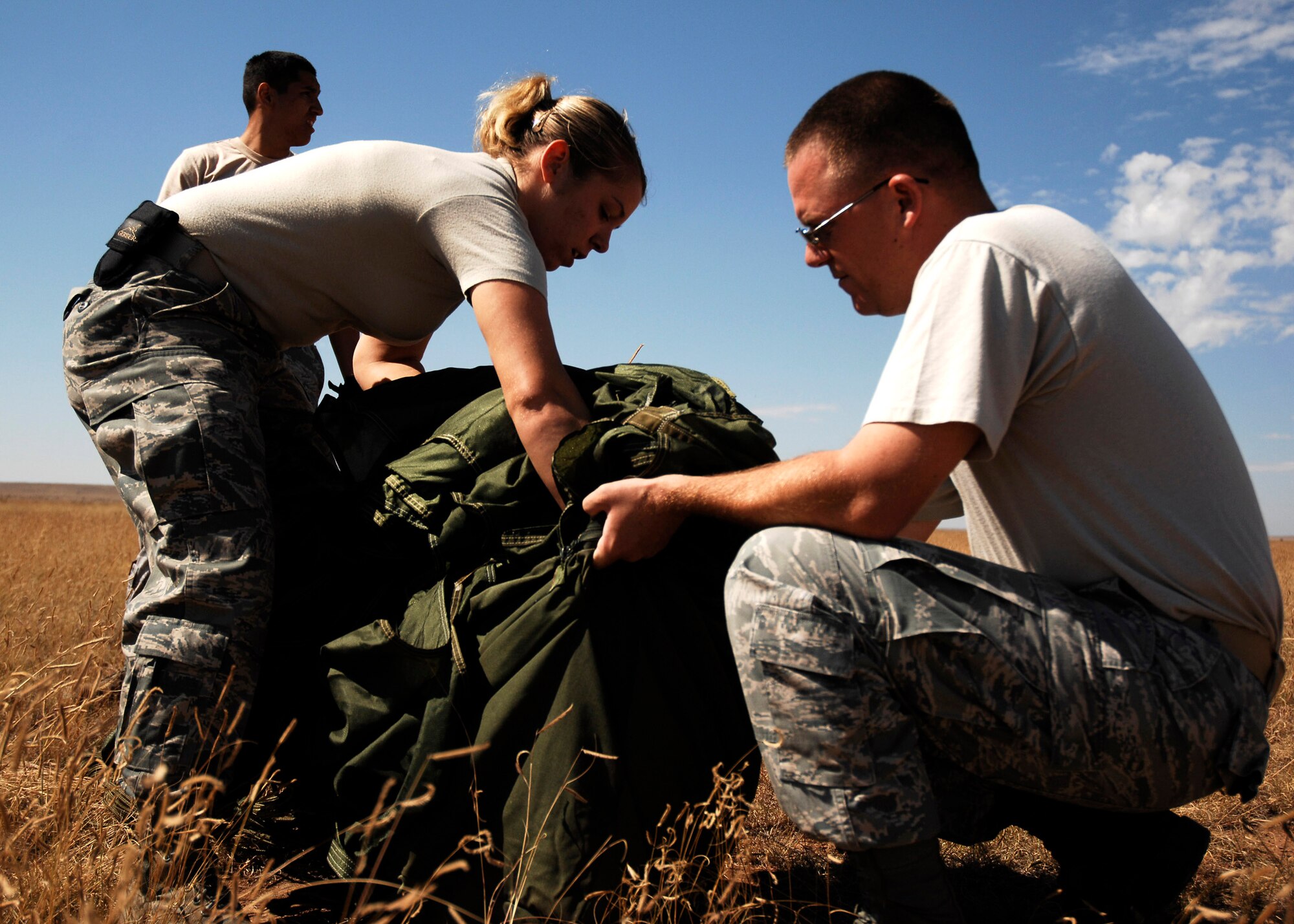 Senior Airman Helen Eberly and Staff Sgt. Jerimy Pickering recover a parachute at the Melrose Air Force Range, N.M., during an exercise Sept. 23. Airmen pack, inspect, and recover the loads that are used for airdrop training. Airman Eberly and Sergeant Pickering are assigned to the  27th Special Operations Logistics Readiness Squadron. (U.S. Air Force photo/Airman 1st Class Evelyn Chavez) 