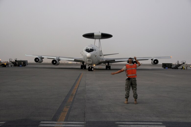 SOUTHWEST ASIA -- A member of the 380th Expeditionary Aircraft Maintenance Squadron gives direction to an E-3 Sentry going on a mission in support of the global war on terrorism here Oct. 4. Some of the personnel aboard are from Canada, Australia and the United Kingdom. This is an exchange program allowing coalition forces to learn from each other both in their respective countries and in a deployed operational environment. This unit is currently deployed from Tinker Air Force Base, Okla. (U.S. Air Force photo/Tech. Sgt. Christopher A. Campbell)(released)