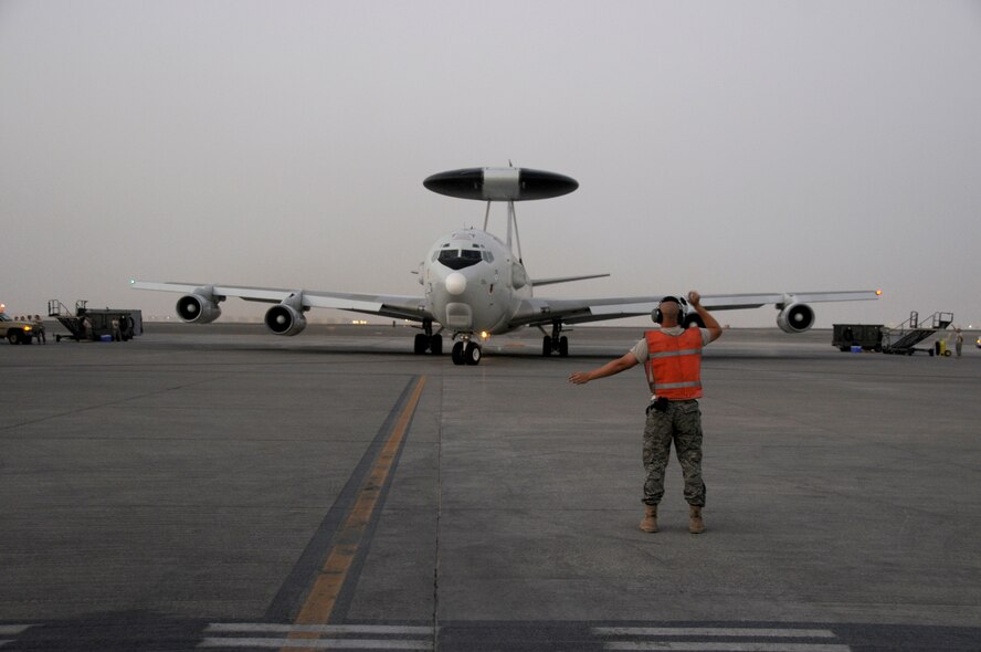 SOUTHWEST ASIA -- A member of the 380th Expeditionary Aircraft Maintenance Squadron gives direction to an E-3 Sentry going on a mission in support of the global war on terrorism here Oct. 4. Some of the personnel aboard are from Canada, Australia and the United Kingdom. This is an exchange program allowing coalition forces to learn from each other both in their respective countries and in a deployed operational environment. This unit is currently deployed from Tinker Air Force Base, Okla. (U.S. Air Force photo/Tech. Sgt. Christopher A. Campbell)(released)