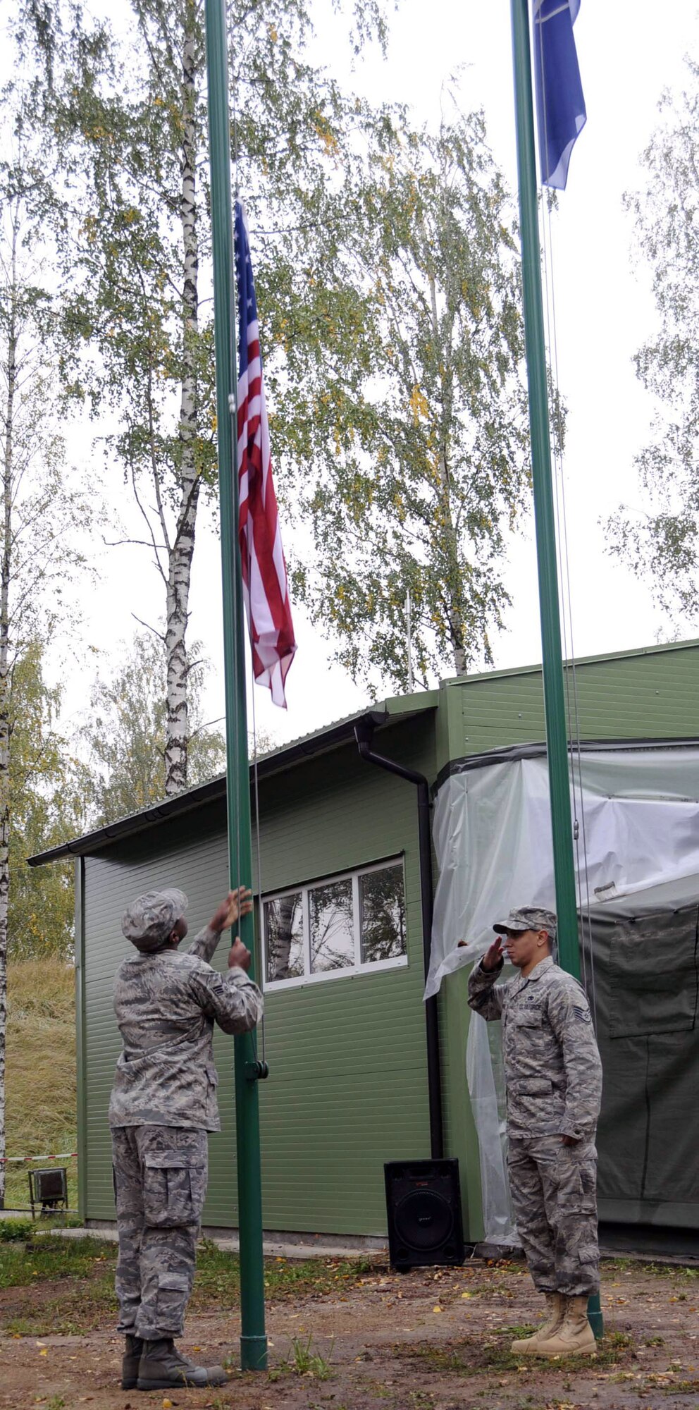 Senior Airman Antonio Huguley raise the U.S. flag over the Quick Reaction Facility as Staff Sgt. Raphael Santos-Montanez salutes the colors. The flag raising was a part of the change-over ceremony marking the first day of the U.S. rotation performing the NATO Baltic air policing mission. Airman Huguley is assigned to the 493d Expeditionary Fighter Squadron PERSCO section. Sergeant Santos-Montanez is assigned to the 493d EFS Quality Assurance section. (U.S. Air Force photo/Tech. Sgt. Jill Lavoie)