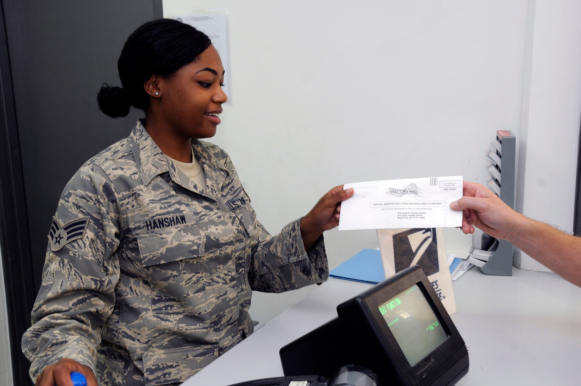 Senior Airman Ashley Hanshaw, a postal clerk with the 379th Expeditionary Communications Squadron at an air base in Southwest Asia, receives a completed absentee ballot that is ready to mail.  Absentee ballots are given top priority for mail processing during election season in order to provide the best chance to have votes count.  Airman Hanshaw, a native of the Bronx, N.Y., is deployed from Dobbins Air Force Base, Ga.  (U.S. Air Force photo/Tech. Sgt. Michael Boquette)