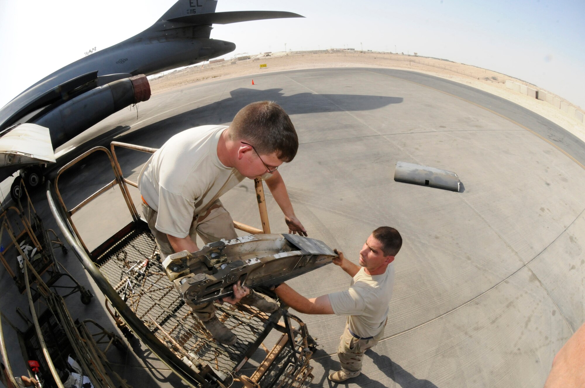 Tech. Sgt. Shaun Carroll hands a removed flap carriage down to Tech. Sgt. Donald Brogan October 5, 2008.  The two, both assigned to the 379th Expeditionary Aircraft Maintenance Squadron, 34th Aircraft Maintenance Unit, are pulling the flaps in order to troubleshoot a flap lock-up problem at an undisclosed air base in Southwest Asia.  The B-1 is often called upon to deliver precision weapons in support of ground troops engaged in Operations Iraqi and Enduring Freedom.  Sergeant Brogan, a native of Saint Charles, Mo., and Sergeant Carroll, hailing from Charleston, S.C., are both deployed from Ellsworth Air Force Base, S.D.  (U.S. Air Force photo by Tech. Sgt. Michael Boquette/Released)