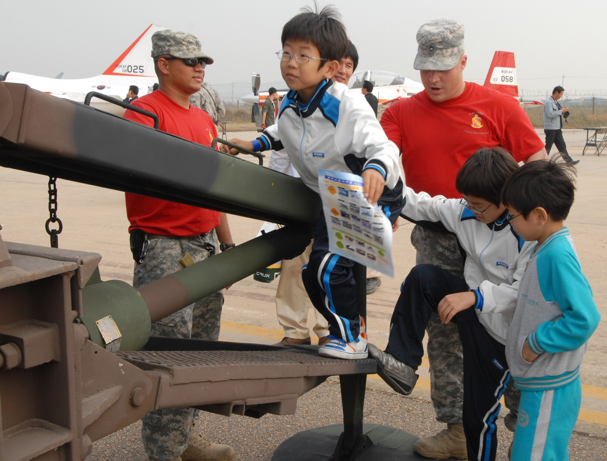 KUNSAN AIR BASE, Republic of Korea -- U.S. Army Sgt. Jonathan Lockett and Private 1st Class Joel Romero help Korean kids on a Patriot during the 2008 Gunsan Airshow here, Oct. 4. The City of Gunsan, 8th Fighter Wing and Republic of Korea Air Forces' 38th Fighter Group hosted the first ever partnership Air Show in Gunsan, Oct. 4-5. (U.S. Air Force photo/Senior Airman Gustavo Gonzalez)