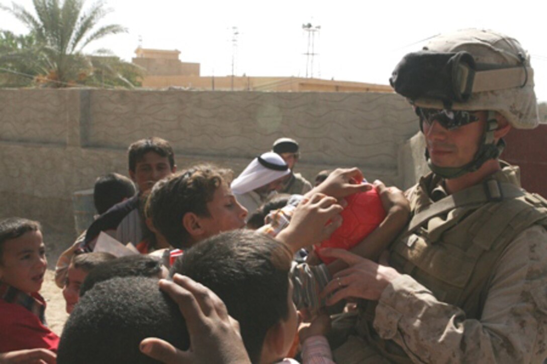 Cpl. Jesse Day, a mortarman with Fox Company, Task Force 2nd Battalion, 2nd Marine Regiment, Regimental Combat Team 5, distributes soccer equipment to Iraqi children at the Al Moaine Elementary School in Rawah, Iraq, Oct. 6. The Marines brought along donations from Rawah's "Friendship City," Towamencin, Pa.