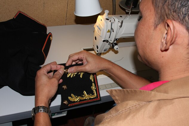 Eddie Benitez, a fitter and tailor for the Marine Corps Community Services Dry Cleaners and Tailor Shop, fits on an ornamentation sleeve to a Marine Officer’s Evening Dress Uniform in preparation for the Marine Corps ball Oct. 7.