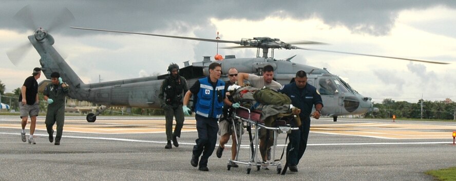 Members of the 31st Rescue Squadron from Kadena Air Base and other medical personnel offload an injured mariner from a Navy helicopter in Guam Sept. 25. The mariner was rescued from a Panamanian freighter about 750 miles north of Saipan. (Courtesy photo) 