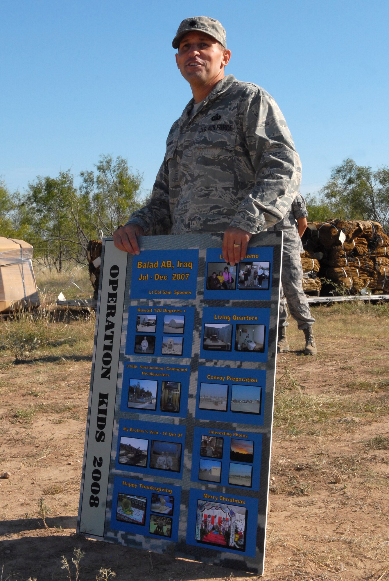 Lieutenant Colonel Samuel Spooner, 17th Mission Support Group deputy commander, displays photographs from various overseas bases as he briefs Operation KIDS particiapants at the War on Terrorism Training Camp Oct. 4. (U.S. Air Force photo by Senior Airman Kasabyan Musal)