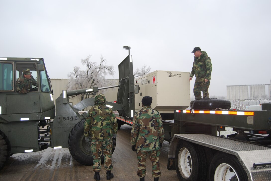 Members of the 190th Civil Engineering Squadron and the 190th Logistics Readiness Squadron load a 100KW generator to support the community health center in Holton, Kan. (photo by: Col Chris Stratmann)