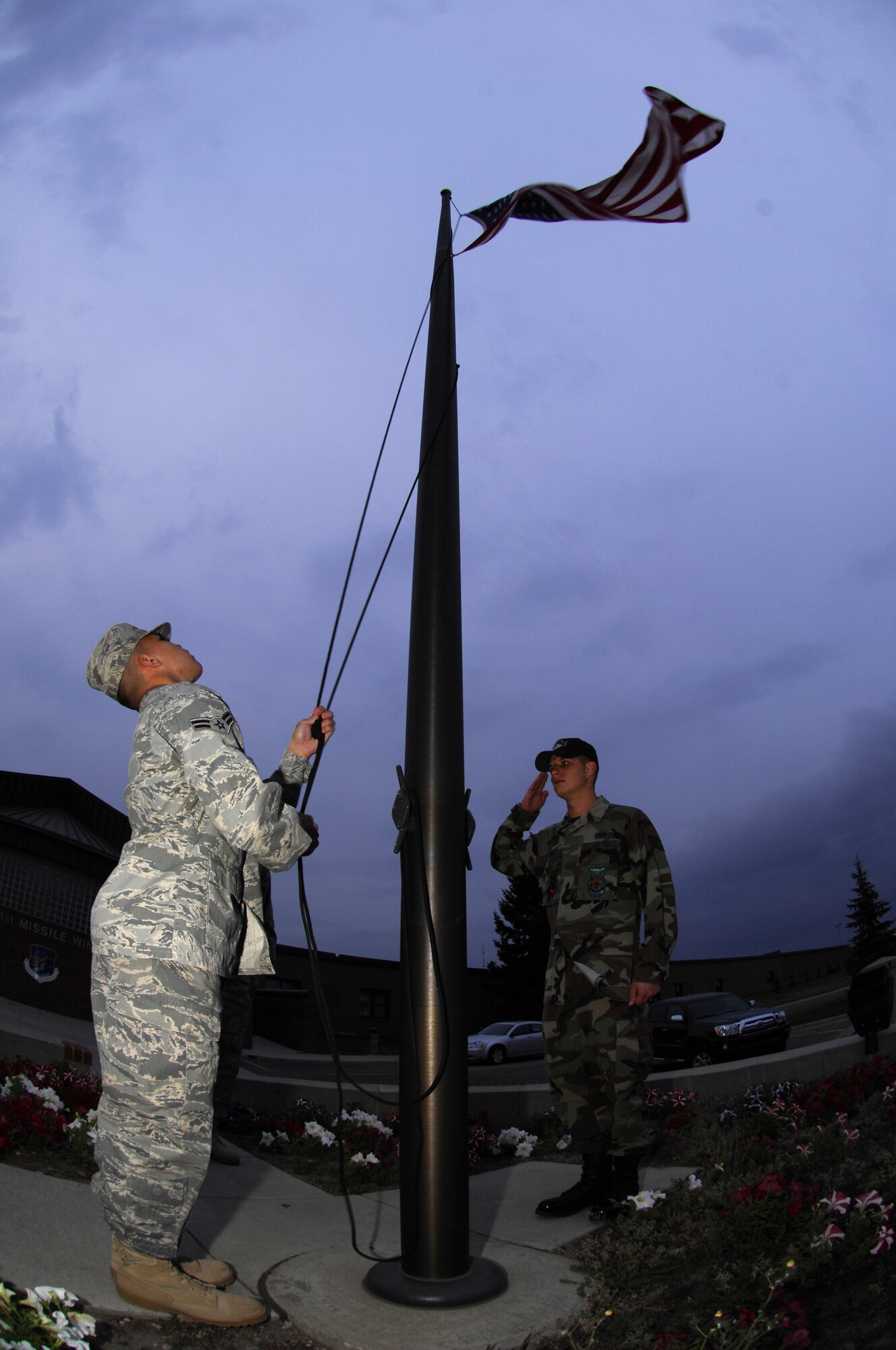 MINOT AIR FORCE BASE, N.D. — Tech. Sgt. Kenneth Kline (center) and Senior Airman Charles Lewis (right) salute as the flag is lowered to half-staff by Airman 1st Class Chris Reyes, here Oct.  5.  The three Airmen, all firefighters from the 5th Civil Engineer Squadron, volunteered to perform the lowering in honor of the National Fallen Firefighters Memorial Weekend.  President George W. Bush approved legislation Oct. 16, 2001, requiring the American Flag to be lowered to half-staff on all federal buildings to memorialize fallen firefighters. (U.S. Air Force photo by Tech Sgt Lee A. Osberry Jr.)  