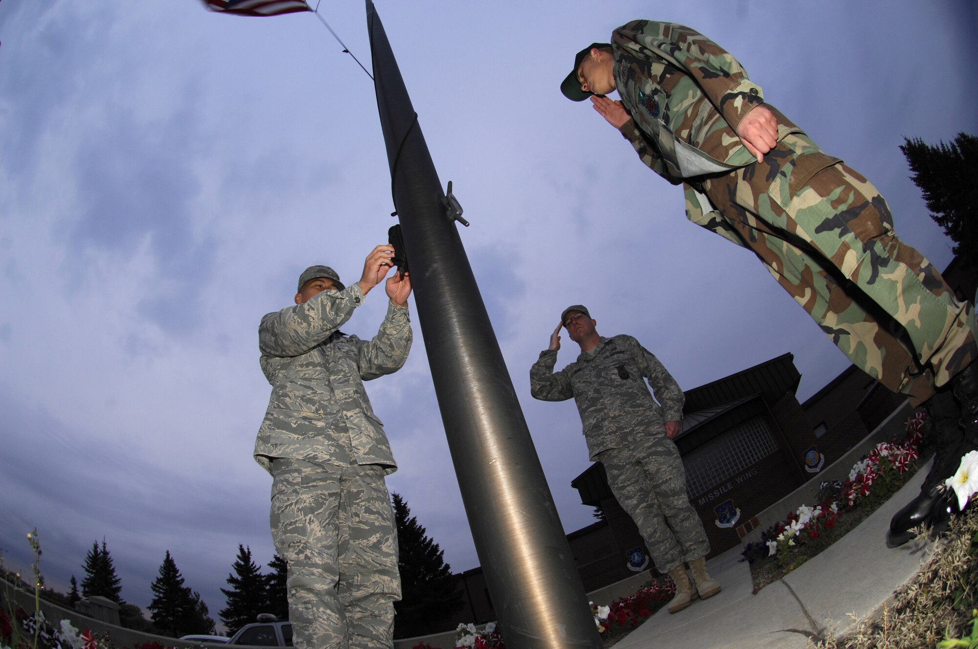 MINOT AIR FORCE BASE, N.D. — Tech. Sgt. Kenneth Kline (center) and Senior Airman Charles Lewis (right) salute as the flag is lowered to half-staff by Airman 1st Class Chris Reyes, here Oct.  5.  The three Airmen, all firefighters from the 5th Civil Engineer Squadron, volunteered to perform the lowering in honor of the National Fallen Firefighters Memorial Weekend.  President George W. Bush approved legislation Oct. 16, 2001, requiring the American Flag to be lowered to half-staff on all federal buildings to memorialize fallen firefighters. (U.S. Air Force photo by Tech Sgt Lee A. Osberry Jr.)  