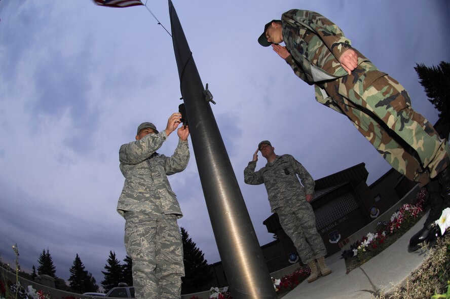MINOT AIR FORCE BASE, N.D. — Tech. Sgt. Kenneth Kline (center) and Senior Airman Charles Lewis (right) salute as the flag is lowered to half-staff by Airman 1st Class Chris Reyes, here Oct.  5.  The three Airmen, all firefighters from the 5th Civil Engineer Squadron, volunteered to perform the lowering in honor of the National Fallen Firefighters Memorial Weekend.  President George W. Bush approved legislation Oct. 16, 2001, requiring the American Flag to be lowered to half-staff on all federal buildings to memorialize fallen firefighters. (U.S. Air Force photo by Tech Sgt Lee A. Osberry Jr.)  