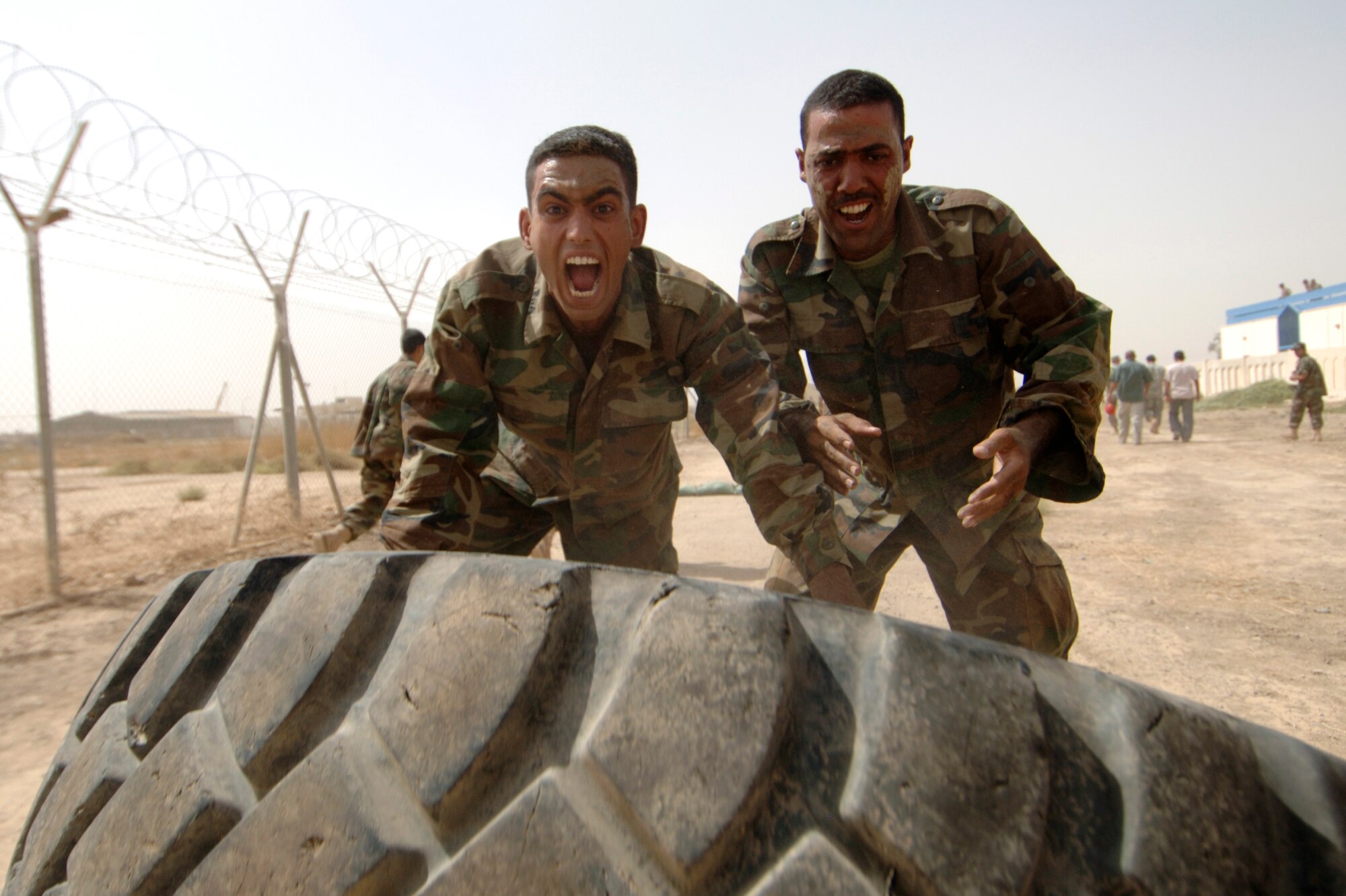 AL TAJI AIR BASE, Iraq -- Iraqi warrant officers flip a tire during their run of the Iraqi air force basic military training tactical course at Al Taji Air Base, Iraq on Sept. 27. The tactical course tests their ability to work as a team and negotiate a variety of obstacles. (U.S. Air Force photo/Staff Sgt. Paul Villanueva II)
