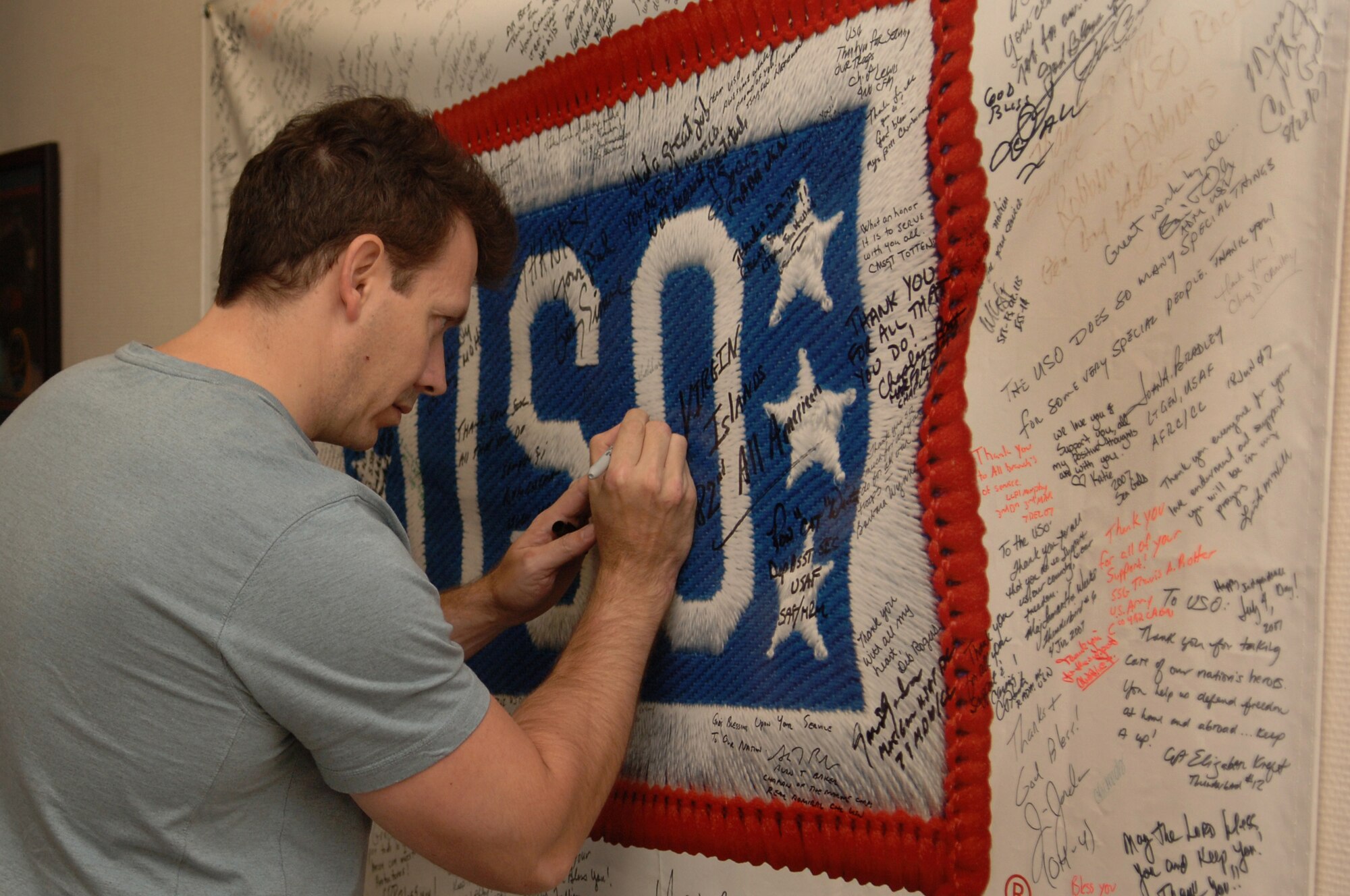 Tom Richmond, MAD Magazine artist, signs the USO's distinguished visitors banner at the Contingency Aeromedical Staging Facility, Ramstein Air Base, Germany, Oct. 2, 2008. Mr. Richmond was one of eight professional cartoonist from the National Cartoonist Society that visited the CASF as part of a morale tour in cooperation with the USO. (U.S. Air Force photo by Airman 1st Class Tony R. Ritter) (Released)