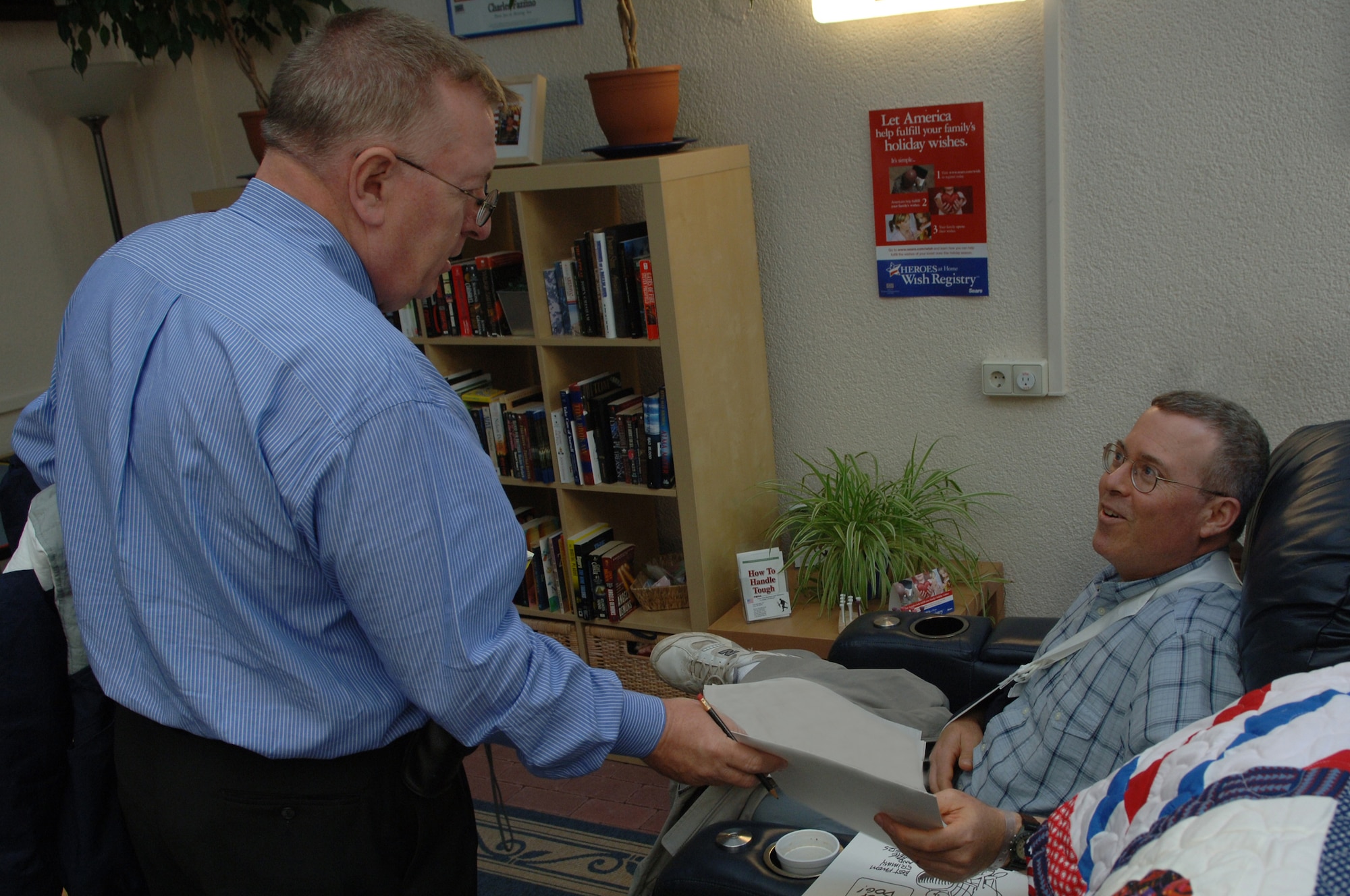Bruce Higdon, Army cartoonist and artist of the Punderstatements, gives U.S. Army Capt. Sean Holland , attorney with the Judge Advocate General, a characture that he sketched at the CASF USO, Ramstein Air Base,Germany, Oct. 2, 2008. Capt. Holland was injured while deployed to Camp Cropper in Iraq. (U.S. Air Force photo by Airman 1st Class Tony R. Ritter) (Released)