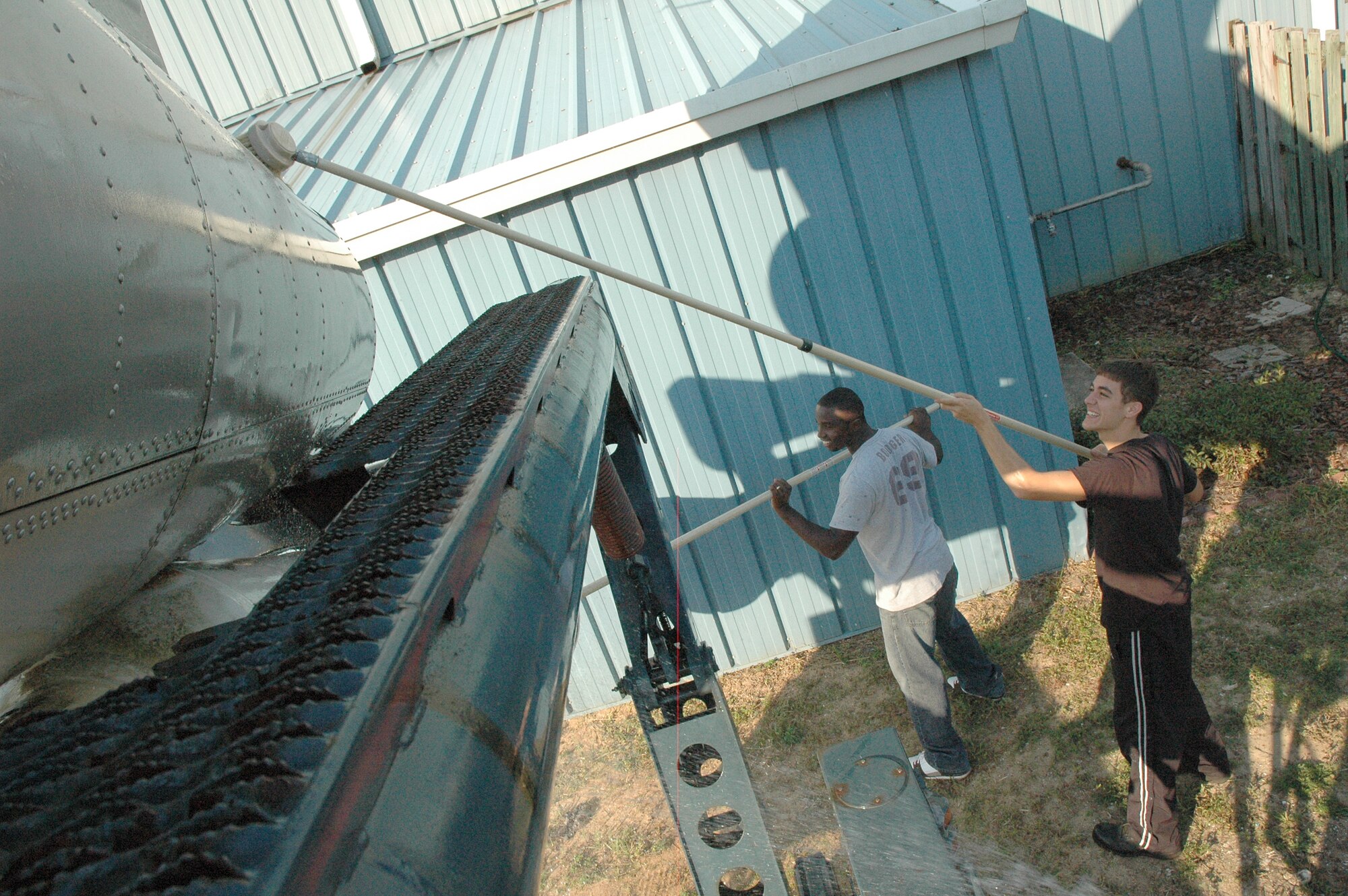 (Left to right) Staff Sgts. Emmanuel Smith and Benjamin Dartez, 46th Maintenance Squadron, scrub dirt, grim and rust off of a static MACE display at the Air Force Air Armament Museum as part of the Adopt-a-Plane initiative. (U.S. Air Force photo/Staff Sgt. Stacia Zachary)