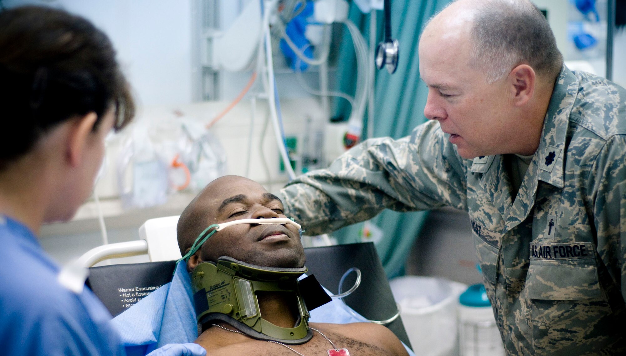 BAGRAM AIR FIELD, Afghanistan -- Ch. (Lt. Col.) Carl Yost, 455th Air Expeditionary Wing, prays for and comforts Army Sgt. 1st Class Cedric Gray here Oct. 2. Chaplain Yost helped the injured soldier stay calm while the hospital staff tended to his wounds. Chaplain Yost is of the Evangelical Luteran Churches of America, deployed from the 315th Air Wing, Charleston Air Force Base, S.C., and hails from Huntersville, N.C. (U.S. Air Force photo by Staff Sgt. Samuel Morse/Released)