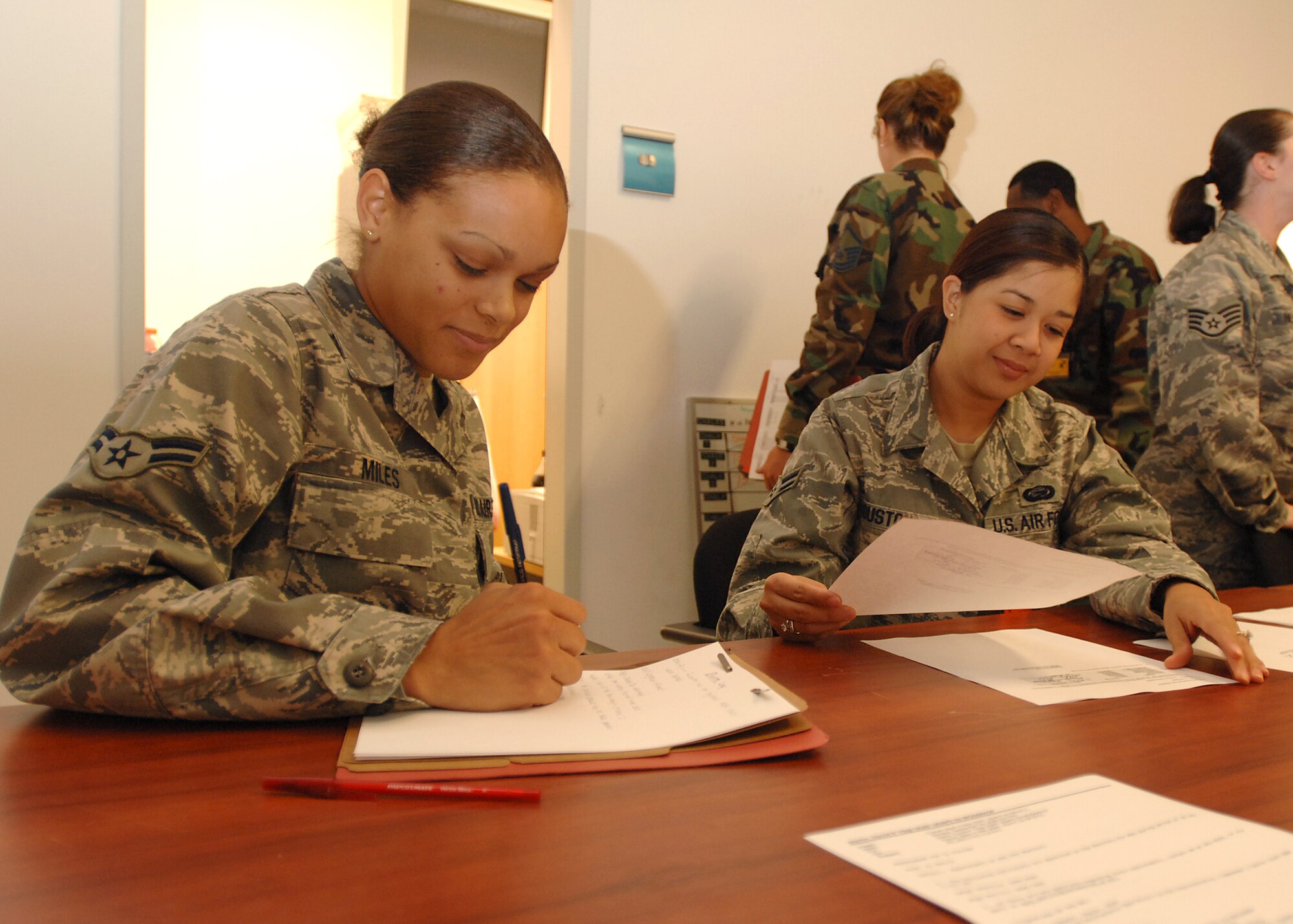SPANGDAHLEM AIR BASE, Germany -- Airmen 1st Class Jamie Miles and Sheryll Houston, 52nd Force Support Squadron, review information for deployers during the Personnel Deployment Function portion of the Phase I exercise at Spangdahlem Air Base on Sept. 29, 2008. Spangdahlem AB conducted a base-wide exercise to test the readiness of personnel for deployment. (U.S. Air Force photo by Airman 1st Class Nathanael Callon)