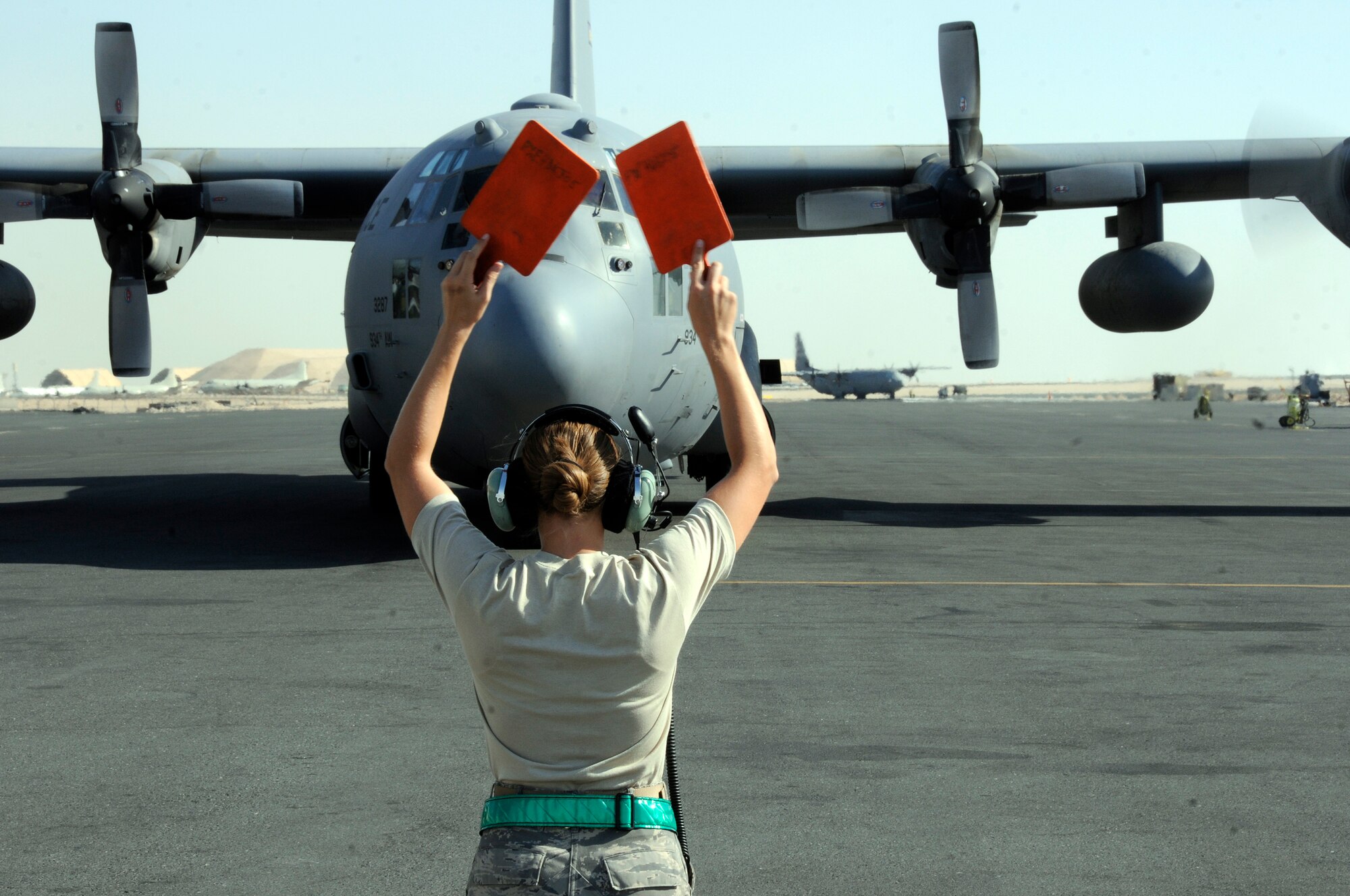 Tech. Sgt. Amber Meyer, 379th Expeditionary Aircraft Maintenance Squadron, 746th Aircraft Maintenance Unit, directs an incoming C-130 Hercules to a stop October 6, 2008.  The aircraft is stopped then backed into a parking spot at an undisclosed air base in Southwest Asia.  The C-130 Hercules primarily performs the tactical portion of the airlift mission. The aircraft is capable of operating from rough, dirt strips and is the prime transport for air dropping troops and equipment into hostile areas in support of Operations Iraqi and Enduring Freedom and Joint Task Force-Horn of Africa.  Sergeant Meyer a native of Hudson, Wis., is deployed from the Minneapolis-St. Paul Air Reserve Station, Minn.  (U.S. Air Force photo by Tech. Sgt. Michael Boquette/Released)