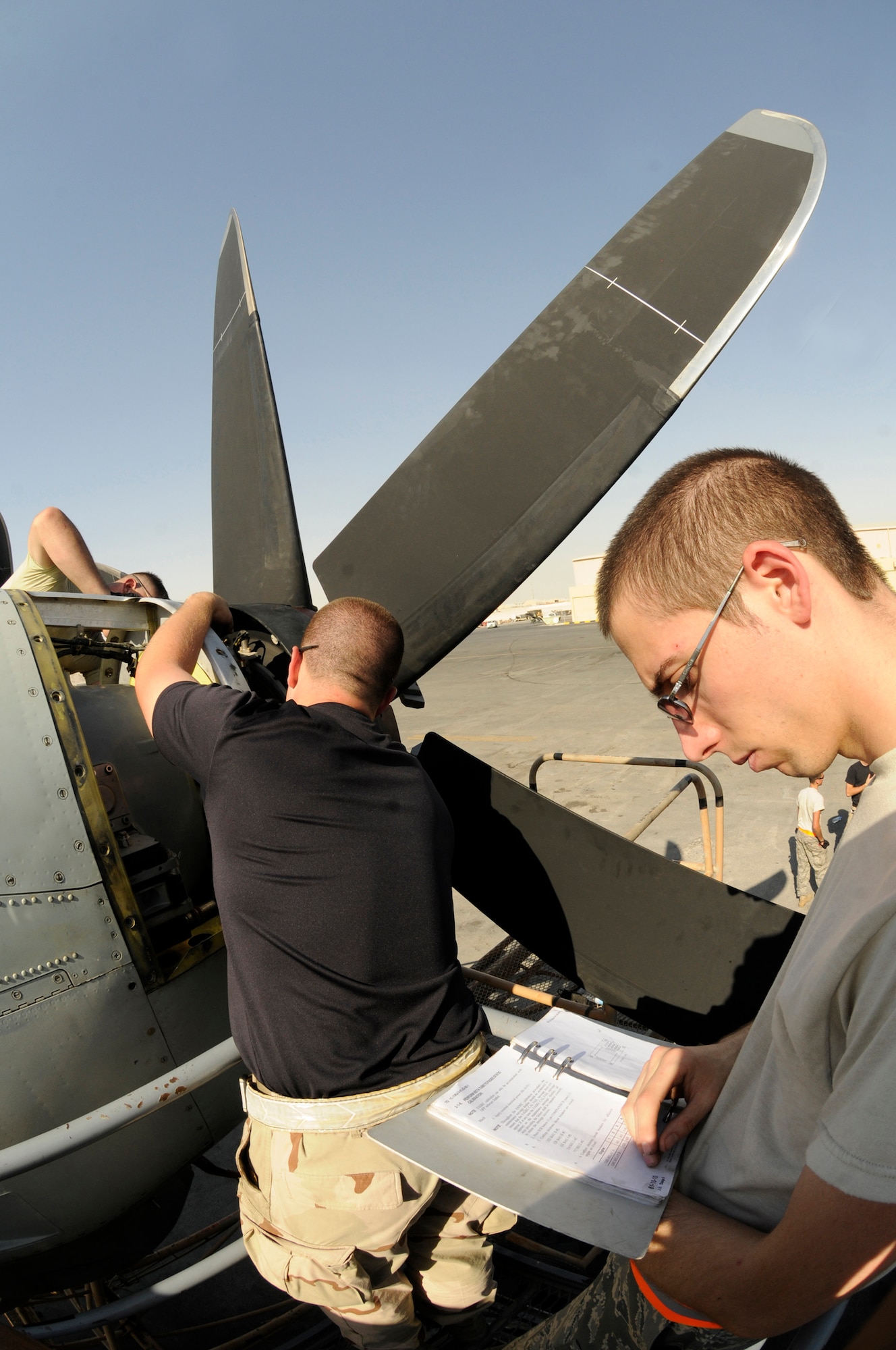 Airman 1st Class Christopher Heyer and Airman 1st Class Zachary Resare, torque down a C-130J propeller while Airman 1st Class Jonathan Barrett reviews the technical orders for changing propellers Oct. 6, 2008 at an undisclosed air base in Southwest Asia.  Airmen Heyer and Resare are crew chiefs and Airman Barrett is a communication navigation specialist; all are assigned to the 379th Expeditionary Aircraft Maintenance Squadron. Maintainers assigned to the EAMXS ensure aircraft are ready to fly missions in support of Operations Iraqi and Enduring Freedom and Joint Task Force-Horn of Africa.  Airman Heyer, a native of Wichita, Wash., Airman Resare, a native of Oregon City, Ore., and Airman Barrett, a native of Austin, Ind., are all deployed from Little Rock Air Force Base, Ark. (U.S. Air Force photo by Staff Sgt. Darnell T. Cannady/Released)