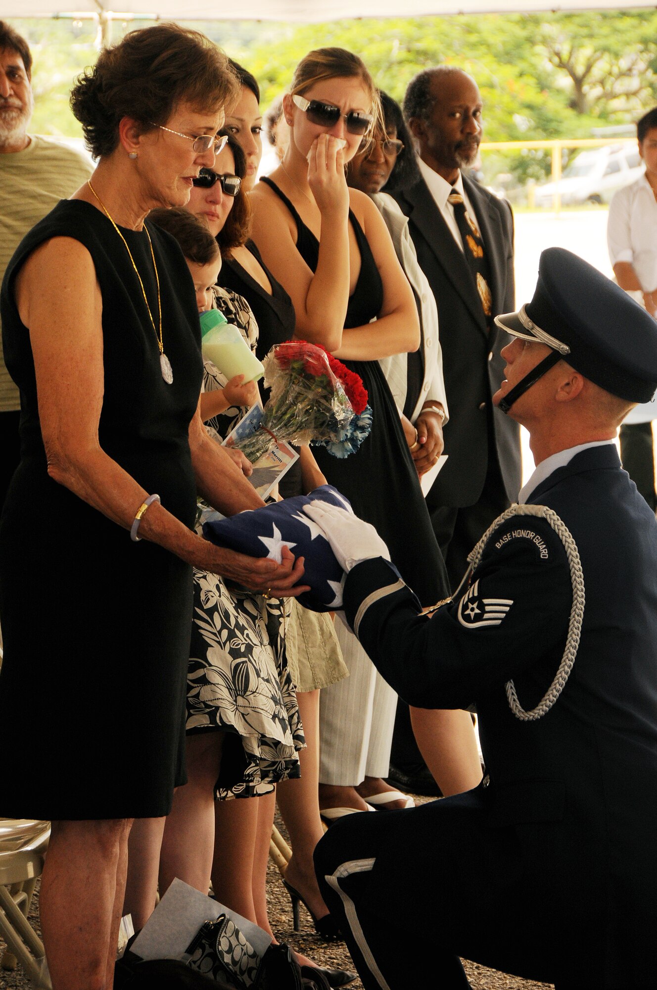 ANDERSEN AIR FORCE BASE, Guam - United States Air Force Honor Guard member Staff Sgt. Noah Bolton presents the American flag to Ann Merritt while the 21-gun salute is rendered during Col. Walter "Tony" Merritt's memorial service at the John F. Kennedy High School in Tammuning, Guam, Oct. 4. Colonel Merritt retired from active duty in 1979 but never left the service. He gave back to the community by serving 28 years as a Junior Reserve Officer's Training Corps instructor at JFK High School and Air Force Liaison Officer to the Air Force Academy. (U.S. Air Force photo by Airman 1st Class Courtney Witt)