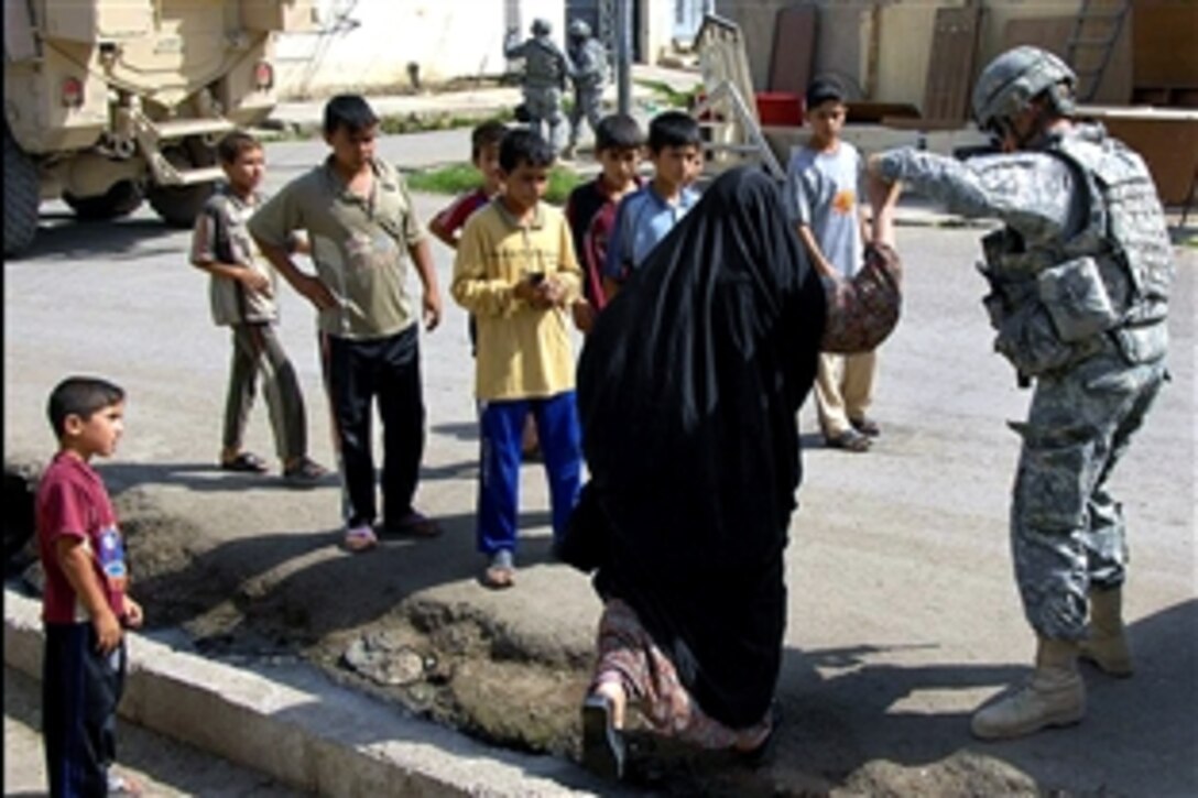 U.S. Army Staff Sgt. Jon Anderstrom helps an elderly Iraqi woman cross a curb while he meets with local shop owners at Cedar Market, Mosul, Iraq, Sept. 21, 2008. Anderstrom is assigned to Company C, 1st Battalion, 8th Infantry Regiment.