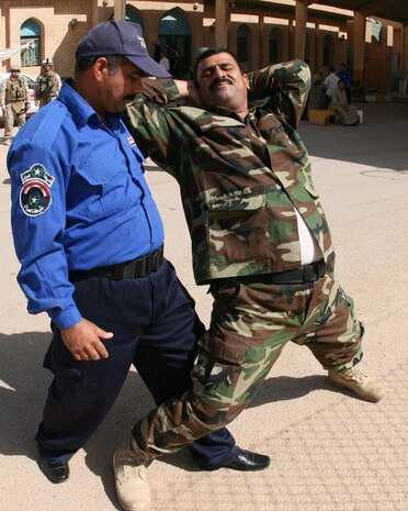 An Iraqi border police officer (front, left) demonstrates a restraint technique in the process of searching a subject during a training exercise at the Port of Trebil, Iraq, Oct. 7.  Staff Sgt. Anthony Macias, a Marine Corps Martial Arts Program instructor with the Trebil Port of Entry Transition Team, incorporated parts of MCMAP into the training for Iraqi Security Forces.  Trebil is located in western al-Anbar province, on the country's border with Jordan.::r::::n::