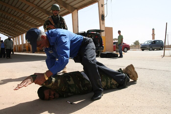 Commissioner Karim Shukur Mahmood, a 27-year veteran of the Iraqi Customs Police, demonstrates a cuffing procedure during a practical application exercise at the Port of Trebil, Iraq, on the Iraqi-Jordanian Border Oct. 7.  A group of 26 Iraqi officials and police officers responsible for all vehicle traffic and commerce coming into and departing Iraq through the Port of Trebil recently went through a course that was taught by Marines with the Trebil Port of Entry border transition team.