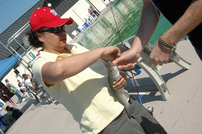 Rose Guevara removes the hook from a striped bass with the help of Airman Mike Case at the base pool Oct. 4. The Charleston AFB Fishing Derby was an opportunity for base members to fish for fun and have lunch at a fish fry. Ms. Guevara works at the Arts and Crafts Center and Airman Case is assigned to the 373rd Training Squadron Det. 5. (U.S. Air Force photo/Staff Sgt. Sam Hymas)