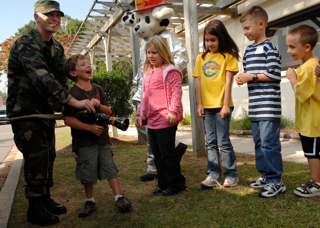 Airman 1st Class William Hook shows Andrew Marabella how to operate a water hose from a fire truck at Youth Programs on Charleston AFB Oct. 7. Firefighers came out to perform a fire drill, show the children the firetruck and let them meet Sparky during Fire Prevention Week. Airman Hook is a firefigher with the 437th Civil Engineer Squadron and Andrew is the son of Erica and Staff Sgt. Andrew Marabella. (U.S. Air Force photo/Airman 1st Class Katie Gieratz)