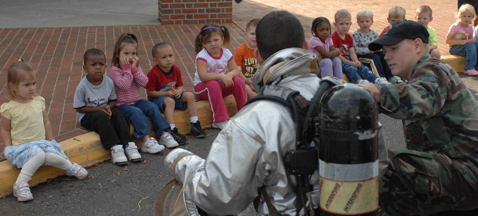 LANGLEY AIR FORCE BASE, Va. -- Airman 1st Class Gaylord Range, 1st Civil Engineer Squadron firefighter and Staff Sgt. Luke Rogan, 1st CES crew chief, show the children what kind of gear firefighters use to help protect them against fires Oct. 6.  The firefighters taught the children about fire prevention and what to do in an emergency situation.   (U.S. Air Force photo/Airman 1st Class Zachary Wolf)