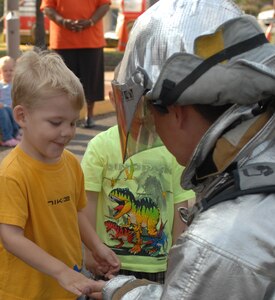 LANGLEY AIR FORCE BASE, Va. – Wesley, son of Senior Airman Michelle Carson from the 1st Dental Squadron, gives Airman 1st Class Gaylord Range, 1st Civil Engineer Squadron firefighter, a high five after seeing Airman Range don his fire protection gear Oct. 6.  The firefighters taught the children at Langley's Russ Child Development Center about fire prevention and what to do in an emergency situation.  (U.S. Air Force photo/Airman 1st Class Zachary Wolf)