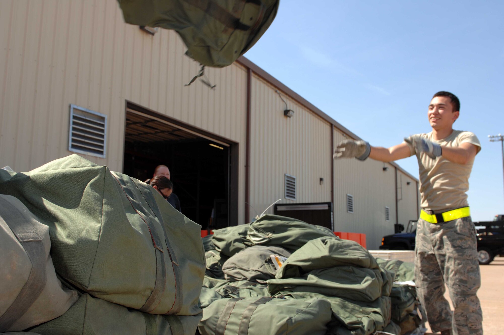 DYESS AIR FORCE BASE, Texas — Airman 1st Class Marco Elizondo, 7th Logistics Readiness Squadron, tosses a “C” bag onto a pallet being prepared for loading Oct. 5. Palletizing cargo is one of the many processes performed in preparation to deploy military personnel. (U.S. Air Force photo/Senior Airman Domonique Simmons)