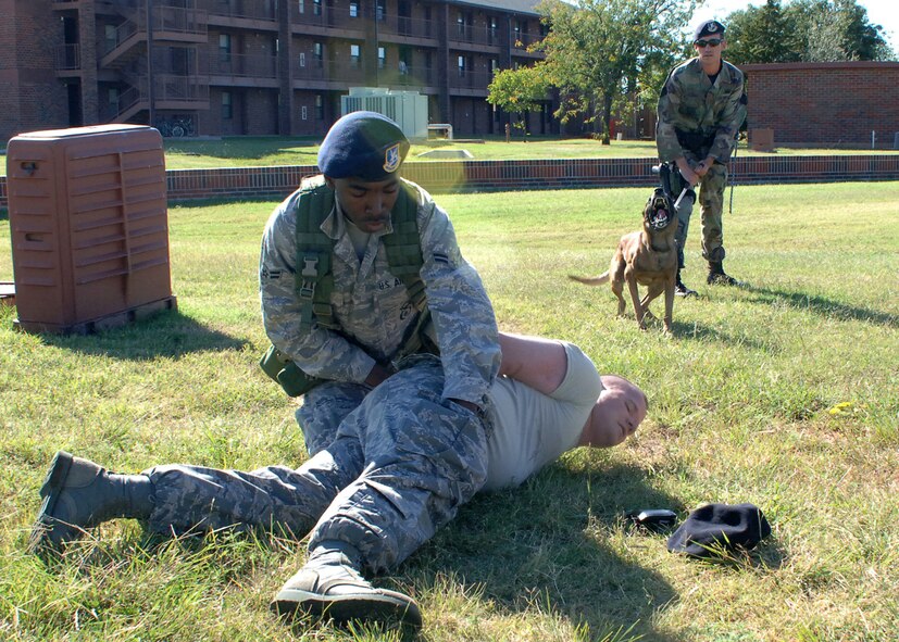 DYESS AIR FORCE BASE, Texas -- Airman 1st Class Jawaiin Gunter searches Senior Airman Benjamin Isom while Staff Sgt. Joshua Covill and his military working dog, Sam, ensure they have a safe environment to work in here Oct. 7. It’s imperative that the 7th Security Forces Squadron conduct all training as though they are “real world” scenarios in order to be properly prepared when they are called upon.  (U.S. Air Force photo/Senior Airman Felicia Juenke)