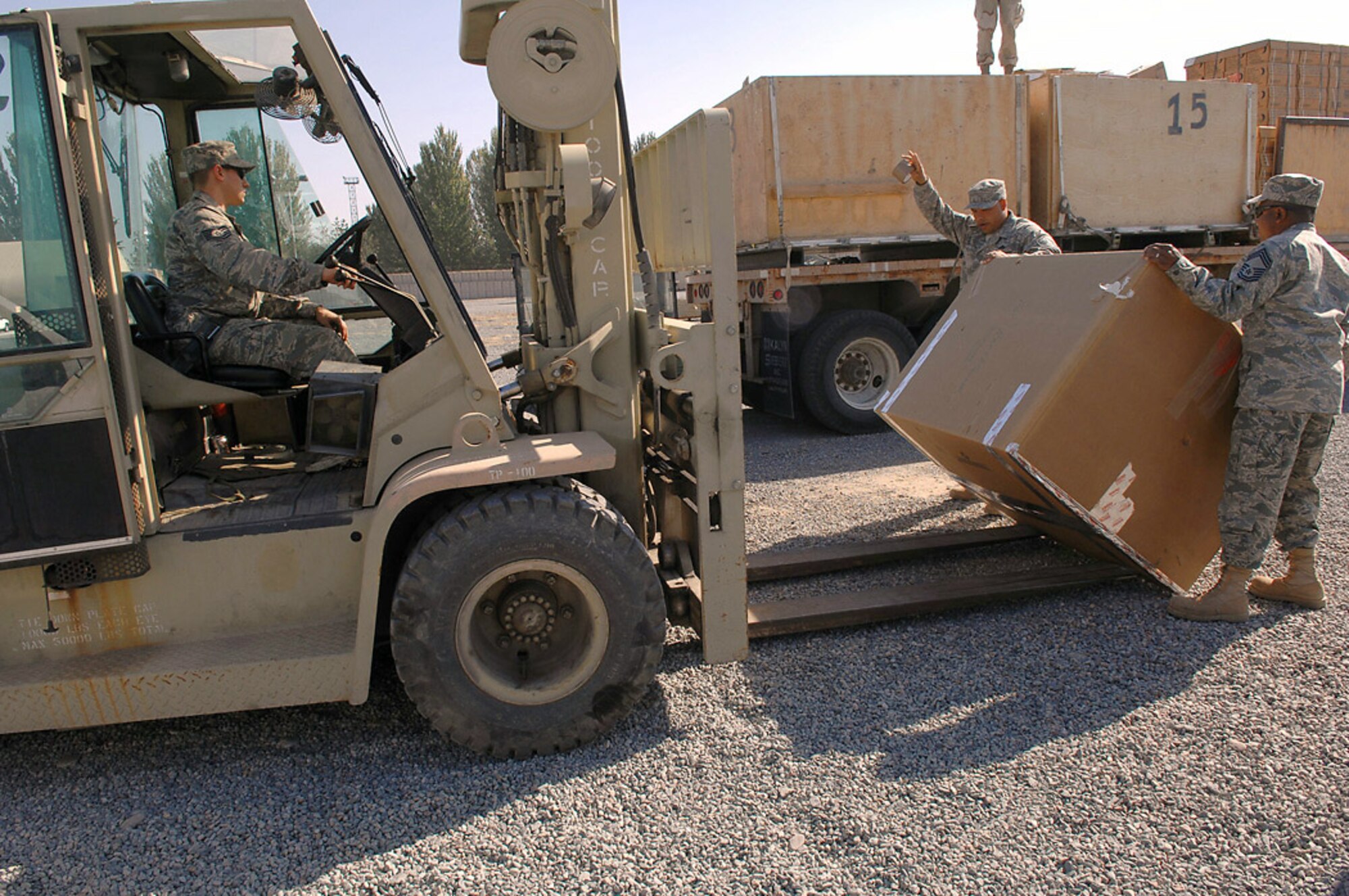 Chief Master Sgt. Stanley Walker and Master Sgt. Otis West tip a box of cold weather gear as forklift driver, Tech. Sgt. Daryl Maniscalco, prepares to place it on a flatbed truck of humanitarian aid intended for survivors of an Oct. 5 earthquake in southern Kyrgyzstan. Airmen from Manas Air Base, Kyrgyzstan, sent thousands of pounds of aid, Oct. 8, that included pallets of food rations, bottled water, surplus military cold weather gear and more than 120 boxes containing 3,000 pounds of adult and children's winter clothing, blankets and toys. A call for personal donations resulted in more than 40 Airmen donating their own blankets they deployed here with. Chief Walker and Sergeant West are both with the 376th Expeditionary Logistics Squadron. (U.S. Air Force photo/Tech. Sgt. Michael Voss)