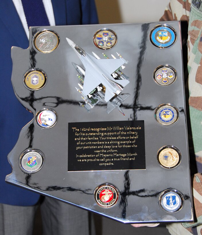 Staff Sgt. Robert Pensas, Master Sgt. Miguel Islas, and Senior Airman Ben Koughn present a chromed plaque they constructed by hand to Mr. William Valenzuela. Using skills and knowledge gained from working in the wing’s metals shop, the Guardsmen constructed this memento in the shape of the state and included challenge coins from various units on base. “I used to be a machinist so this means more to me than you know,” said Valenzuela. (Air National Guard photo by Master Sgt. Dave Neve)