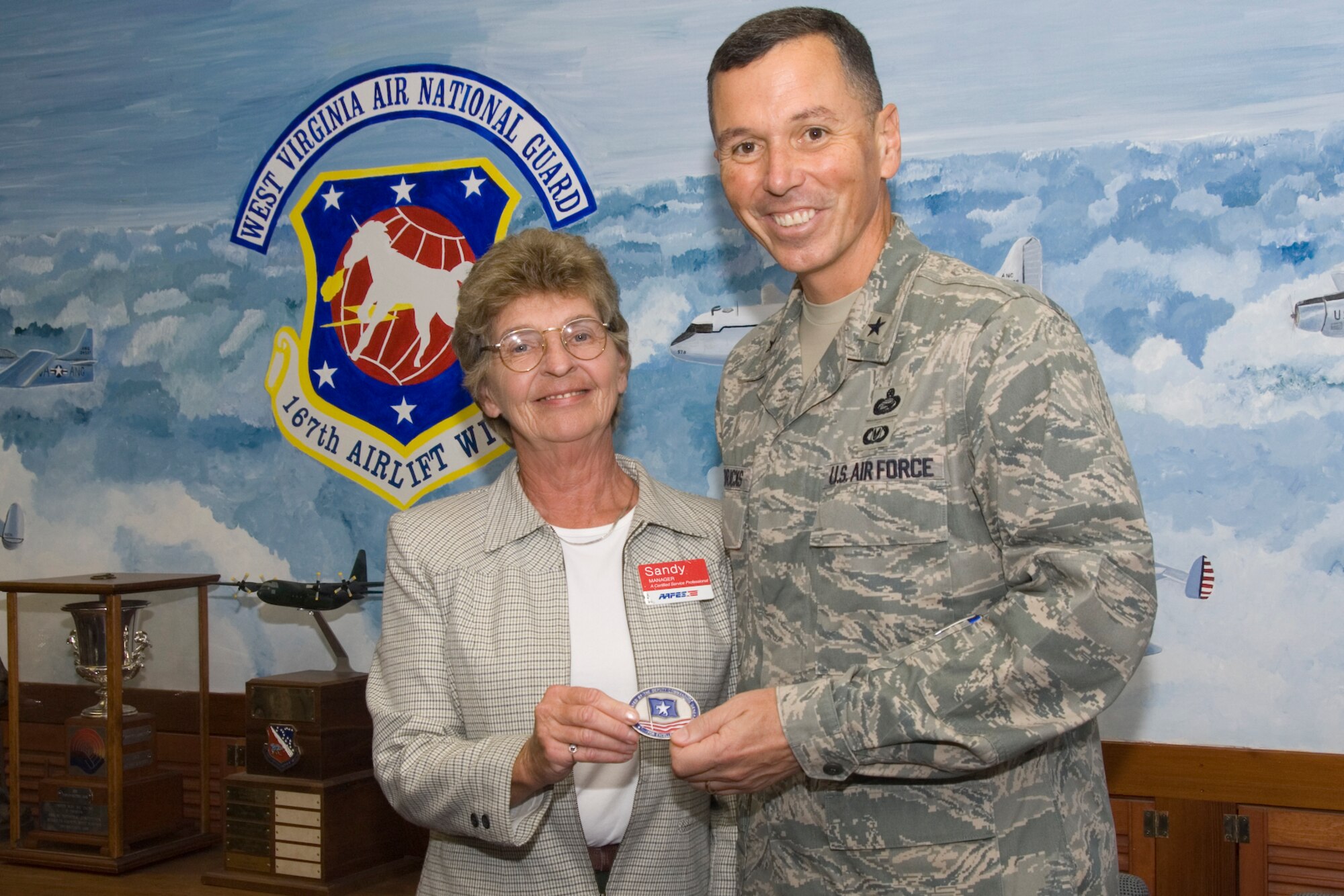 Mrs. Sandy Chrisman, 167th Airlift Wing Shoppette Manager, is presented with Brig. General Fran L. Hendricks' Coin of Excellence. Gen. Hendricks is the Deputy Commanding General for the Army and Air Force Exchange Service (AAFES). His primary reason for visiting the 167th Airlift Wing on Sept. 26 was to ensure that AAFES was providing positive customer service to the Wing and to recognize Mrs. Chrisman for her outstanding performance.