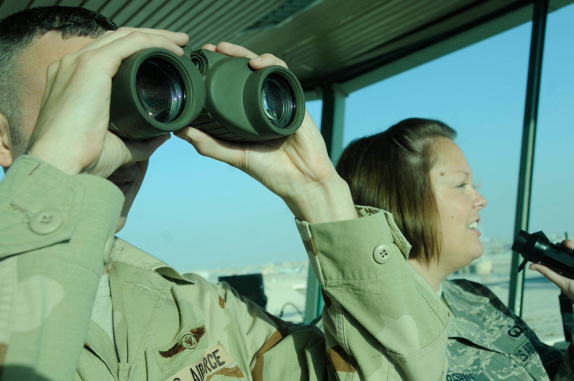 Tech. Sgt. Reggie Rittenhouse uses binoculars to maintain visual contact with incoming aircraft while Staff Sgt. Casandra Marshall grants clearance to an aircraft using the ground control frequency Oct. 7, 2008, at an undisclosed air base in Southwest Asia. Both sergeants are air traffic control supervisors assigned to the 379th Expeditionary Operations Support Squadron and are responsible for safely launching and recovering dozens of aircraft supporting Operations Iraqi and Enduring Freedom and Joint Task Force-Horn of Africa daily. Sergeant Rittenhouse, a native of Philadelphia, Pa., is deployed from Aviano Air Base, Italy, and Sergeant Marshall, a native of Nashville, Ark., is deployed from Minot Air Force Base, N.D. (U.S. Air Force photo by Staff Sgt. Darnell T. Cannady/Released)