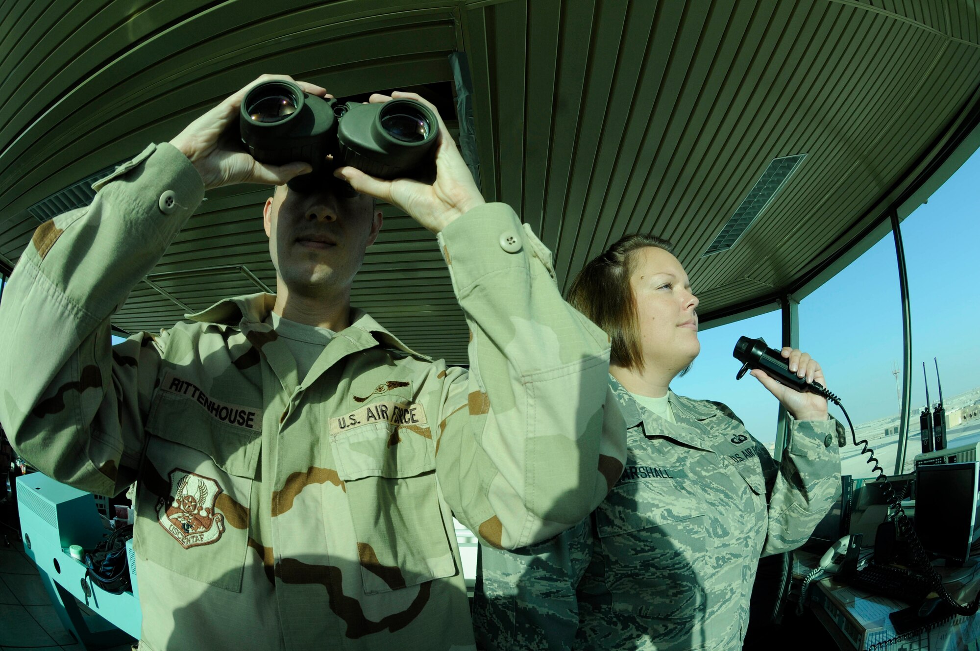 Tech. Sgt. Reggie Rittenhouse uses binoculars to maintain visual contact with incoming aircraft while Staff Sgt. Casandra Marshall grants clearance to an aircraft using the ground control frequency Oct. 7, 2008, at an undisclosed air base in Southwest Asia. Both sergeants are air traffic control supervisors assigned to the 379th Expeditionary Operations Support Squadron and are responsible for safely launching and recovering dozens of aircraft supporting Operations Iraqi and Enduring Freedom and Joint Task Force-Horn of Africa daily. Sergeant Rittenhouse, a native of Philadelphia, Pa., is deployed from Aviano Air Base, Italy, and Sergeant Marshall, a native of Nashville, Ark., is deployed from Minot Air Force Base, N.D. (U.S. Air Force photo by Staff Sgt. Darnell T. Cannady/Released)