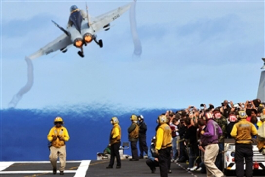 Visitors aboard the aircraft carrier USS Abraham Lincoln watch from behind the flight deck foul lines as an F/A-18C Hornet assigned to the "Vigilantes" of Strike Fighter Squadron 151 launches to participate in a Carrier Air Wing 2 aerial change of command ceremony, Pacific Ocean, Oct. 6, 2008. The USS Lincoln and CVW 2 are returning from a seven-month deployment to the U.S. Navy Fifth Fleet area of responsibility. 