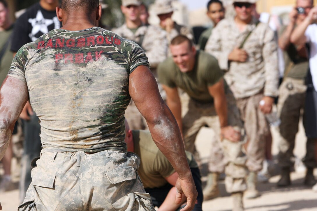 Alex Castro, better known as Militia from the TV show "American Gladiators," stares down the competition after tossing two Marines out of the ring during a round of  "Bull in the Ring" with members of 3rd Battalion, 7th Marine Regiment, Regimental Combat Team 5 at Camp Hit, Iraq, Sept. 8.  After sitting down for lunch and talking to the Marines, the gladiators tested their strength against some of the Marines with some tug-of-war and a few rounds of "Bull in the Ring."::r::::n::