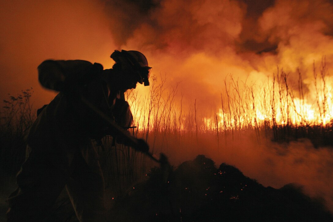 A firefighter from Pendleton's Fire and Emergency Services digs a trench around charred fields to prevent further damage. More than 530 fire fighters on the ground and in the air from across San Diego county worked to extinguish fires on Camp Pendleton, Oct. 8.