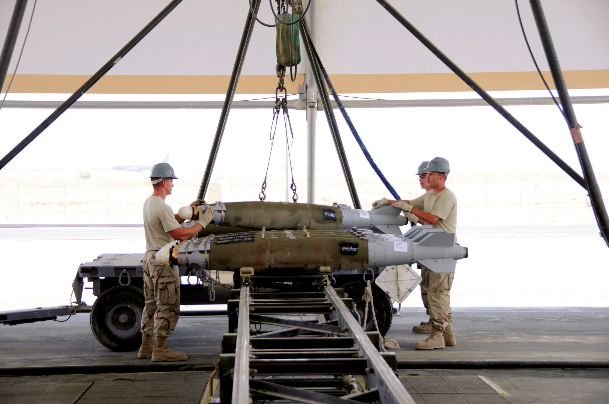 Airman 1st Class Jacob Frank (left), cradles the front of a guided bomb unit-38 as he and Senior Airman Joseph Hibbard guide the bomb into position on a transport cart in Southwest Asia recently. Airman 1st Class Charles Cooksey works the controls of the crane as the team loads a cart of bombs for loading on to aircraft. All three Airmen are from the 379th Expeditionary Maintenance Squadron and are deployed from Ellsworth Air Force Base, S.D. Airman Hibbard is a native of Omaha, Neb., Airman Frank comes from Houghton, Mich., and Airman Cooksey hails from Bainbridge, Ga. (U.S. Air Force photo/Tech. Sgt. Michael Boquette)